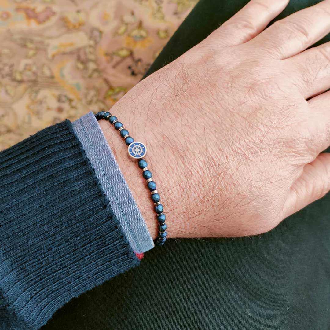 bracciale con sfere e timone nautico in acciaio blu indossato da un uomo - via condotti store